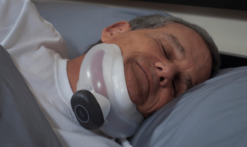 Photo of person laying down sleeping with device attached to their chin.